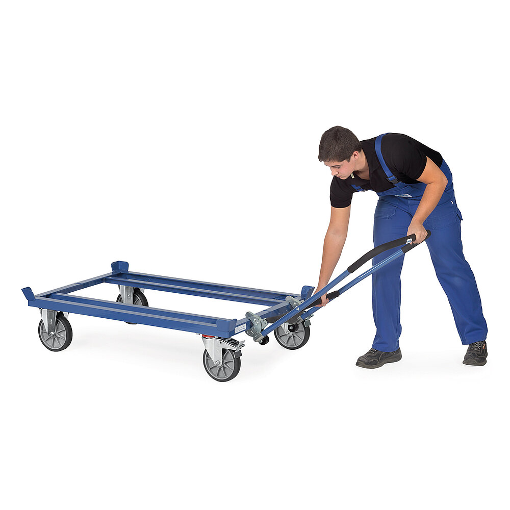 ein Arbeiter in blauer Latzhose klinkt einen Rohrschiebebügel in ein blaues FETRA® Palettenfahrgestell auf weißem Hintergrund Bild 1