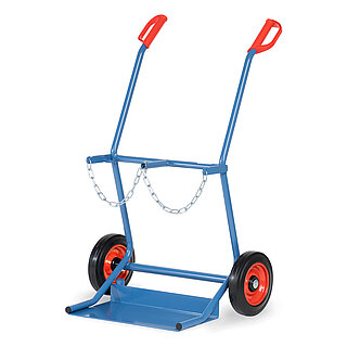 eine breite blaue FETRA® Karre aus Stahlrohr für Stahlflaschentransport mit dreiseitig umrandeter Ladeschaufel, Vollgummi-Bereifung auf roten Felgen, roten Handgriffen und Kettensicherung für zwei stehend platzierte breite Gasflaschen, freigestellt auf weißem Hintergrund