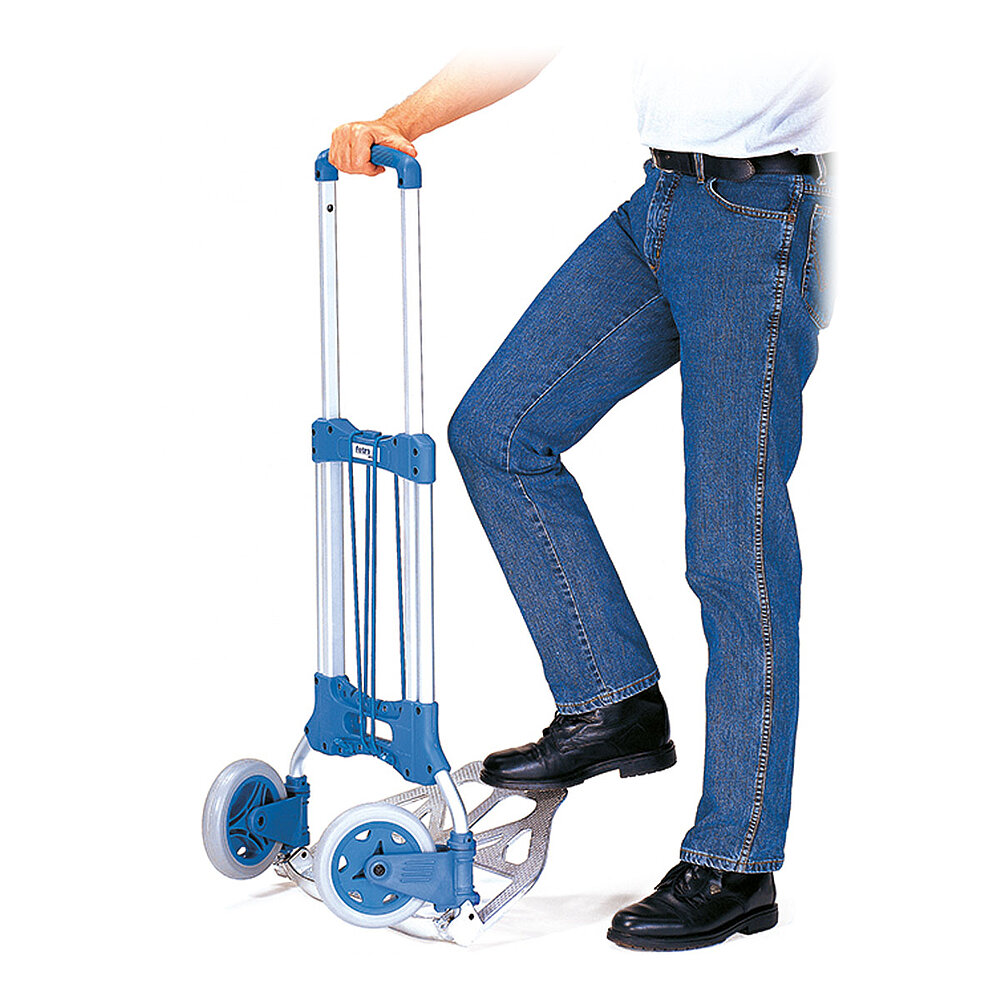Anwendungsdetail eines zusammenklappbaren FETRA® Paketrollers aus silbrigem Aluminiumrohr mit blauem Kunststoffgriff und elastischer Gummisicherungsschnur, gehalten von einem Mann in blauer Jeans auf weißem Hintergrund
