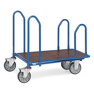 ein blauer FETRA® Plattformwagen mit vier seitlich angebrachten gebogenen Haltebügeln aus Stahlrohr, zwei Bockrollen vorne, zwei feststellbaren Lenkrollen hinten und brauner Ladeplattform aus Holz, freigestellt auf weißem Hintergrund