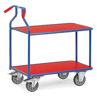 ein blauer FETRA® Magazinwagen aus Stahlrohr mit zwei bündig eingelegten Plattformen aus rotem Holz, nach hinten gebogenen roten Handgriffen, zwei Bockrollen vorne und zwei Lenkrollen hinten, freigestellt auf weißem Hintergrund
