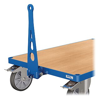 Detailansicht eines blauen FETRA® Plattformwagens aus Profilstahl mit Steckloch an der Ecke, hellem Holzeinlegeboden, feststellbaren Lenkrollen mit dunkelgrauer TPE-Bereifung auf Metallfelge mit Sternmuster, jeweils darüberliegendem, verzinktem Rad-Feststellhebel und einer mittig an der Stirnseite angebrachten, nach oben geklappten Anhängerdeichsel aus blau lackiertem Stahl, freigestellt auf weißem Hintergrund