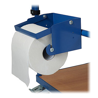 ein blauer FETRA® Papierrollenhalter aus Stahlblech mit von oben mittels Schwerkraft nachführendem Rollenklemmbügel, montiert an einem FETRA® Tischwagen und bestückt mit einer dicken weißen Papierrolle, freigestellt auf weißem Hintergrund