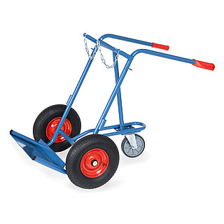 eine breite blaue nach hinten geneigte FETRA® Karre aus Stahlrohr für Stahlflaschentransport mit dreiseitig umrandeter Ladeschaufel, Luftbereifung auf roten Felgen, roten Handgriffen auf nach hinten geknickten Schiebebügeln, Kettensicherung für die Gasflaschen und zusätzlichem dritten stützenden Hinterachs-Lenkrad, freigestellt auf weißem Hintergrund