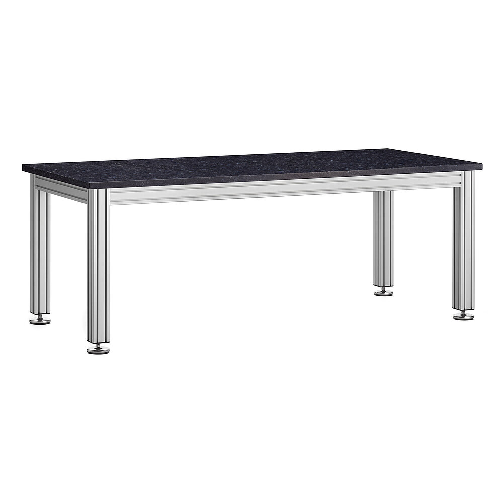 ein längliches Tischgestell aus quadratischem Aluminiumprofil mit vier Tischbeinen und einer massiven dunklen Tischplatte aus Naturstein, aufgestellt auf in die Tischbeine eingeschraubte Nivellierelemente aus Edelstahl, freigestellt auf weißem Hintergrund