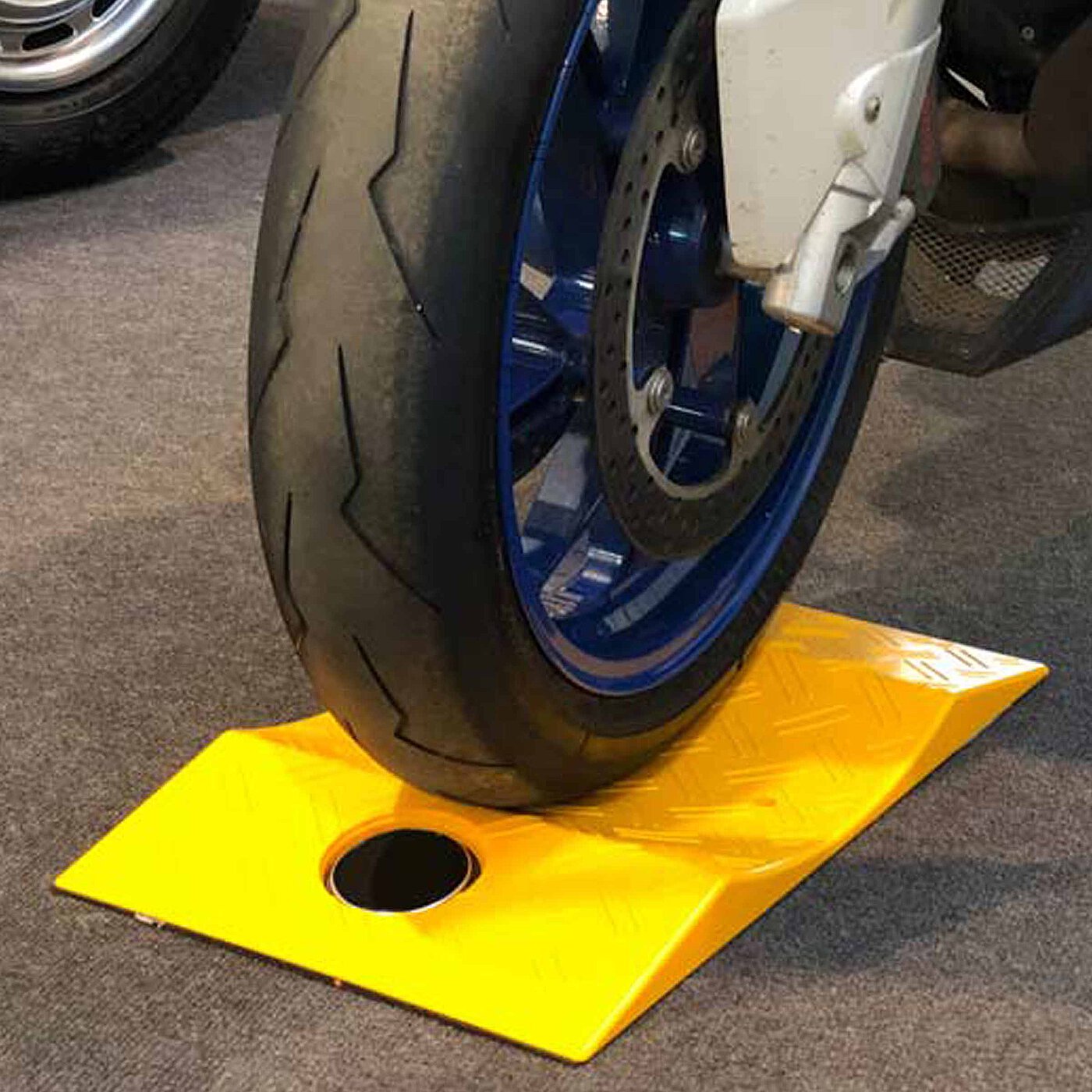 ein gelber konkaver TyreGuard® Reifenschoner aus hochfestem Kunststoff unter einem Motorradreifen