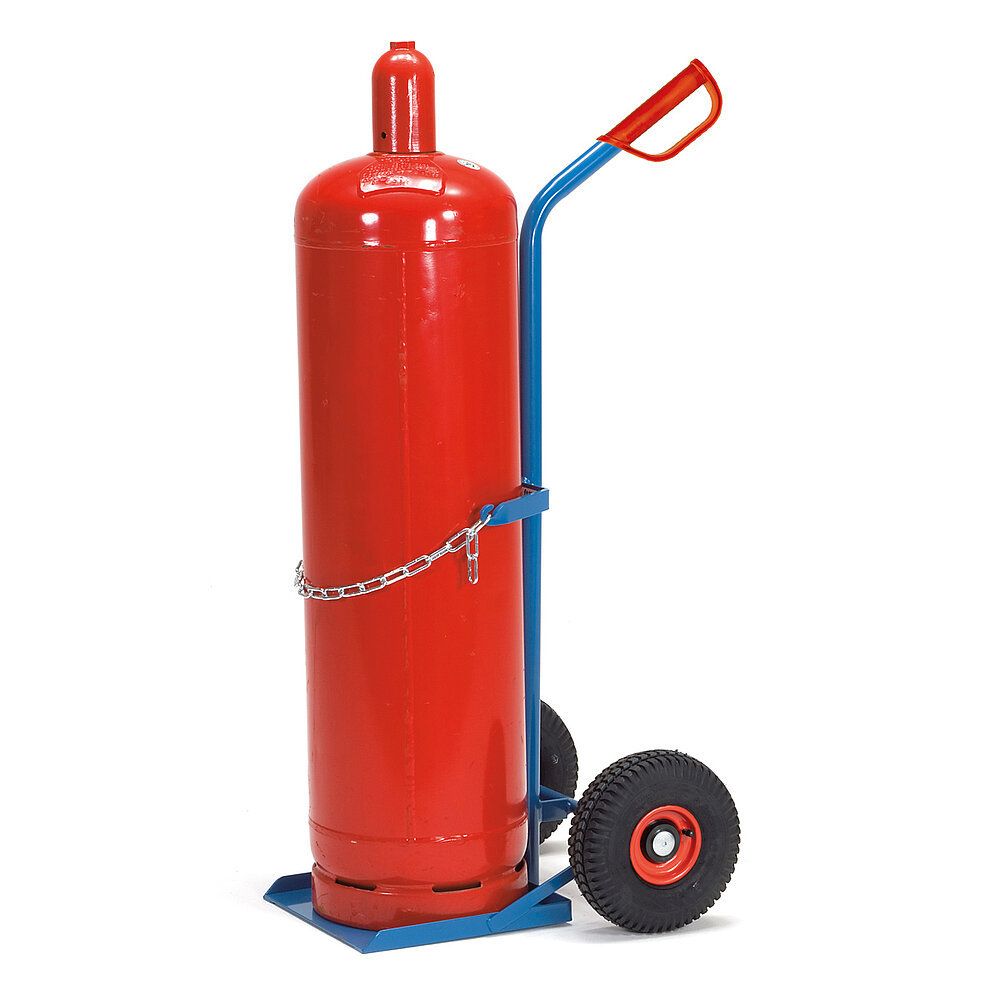 eine blaue FETRA® Karre aus Stahlrohr für Transport von Stahlflaschen sehr großer Durchmesser, mit dreiseitig umrandeter Ladeschaufel, Luftbereifung auf roten Felgen, rotem Handgriff auf nach hinten geknicktem Schiebebügel und Kettensicherung, beladen mit einer großen roten Gasflasche, freigestellt auf weißem Hintergrund