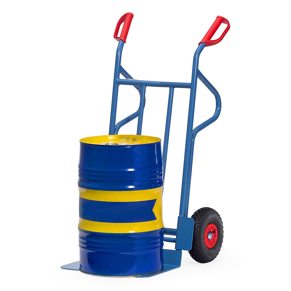 eine blaue FETRA® Sackkarre aus Stahlrohr mit Luftbereifung, Stützkufen für Horizontallage, großer Ladeschaufel, roten Handgriffen und beladen mit einem blau-gelb gestreiften Ölfass auf weißem Hintergrund