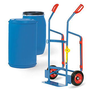 eine blaue FETRA® Karre aus Stahlrohr mit zwei Rädern mit Vollgummi-Bereifung auf roten Felgen, Stahlblechschaufel, roten Handgriffen und rückseitigen Kufen für Horizontallage in Ruheposition, dahinter zwei blaue Fässer aus Kunststoff mit blauem und schwarzem Deckel, freigestellt auf weißem Hintergrund