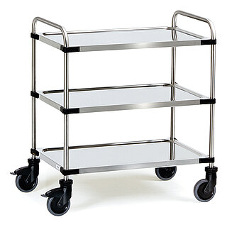 ein silbrig glänzender FETRA® Schiebewagen aus Edelstahlrohr mit drei Etagen, jeweils mit leicht vertieften durchgängigen Edelstahlblechen und vier Lenkrollen, davon zwei feststellbar, freigestellt auf weißem Hintergrund