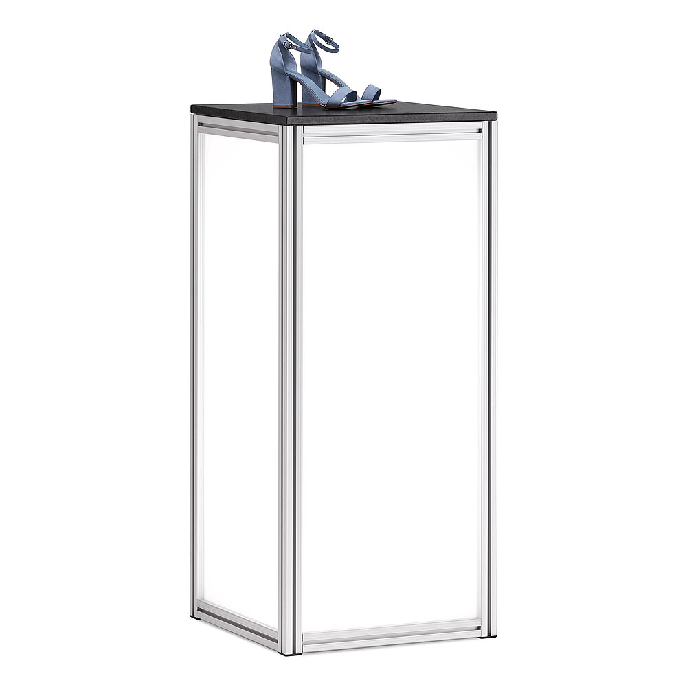 ein quadratischer säulenförmiger Tisch aus Aluminiumprofil mit von innen beleuchteten milchig-transparenten Seitenscheiben und schwarzer Natursteinplatte oben, darauf stehend ein paar blaue Schuhe mit hohen Absätzen, freigestellt auf weißem Hintergrund