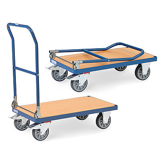 ein blauer FETRA® Klappwagen mit tiefliegender, stahlbandeingefasster rechteckiger Plattform aus hellem Holz, abklappbarem Schiebebügel aus Stahlrohr, zwei Bockrollen vorne, zwei feststellbaren Lenkrollen hinten, und ein zweiter, zusammengeklappter Wagen dahinter, freigestellt auf weißem Hintergrund