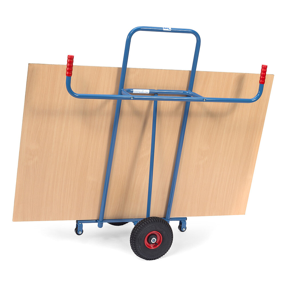 Rückansicht einer blauen FETRA® Karre zum Transport von Platten mit zwei schwarzen Gummireifen, zwei roten Handgriffen und einer großen braunen Holzplatte auf weißem Hintergrund