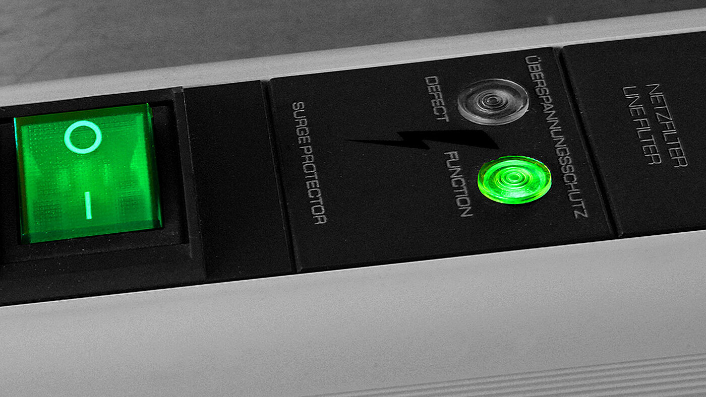 Detailaufnahme einer Stromsteckerleiste mit grün leuchtendem Schalter
