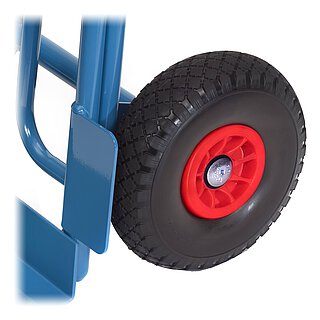 Detailansicht eines schwarzen FETRA® Rades mit profilierter, pannensicherer Polyurethanvollbereifung auf roter Kunststofffelge und schwarzer Nabe, montiert an einen blau pulverbeschichteten Transportkarren, freigestellt auf weißem Hintergrund