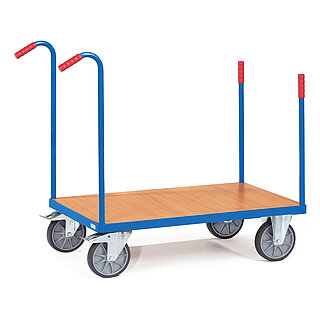 ein blauer FETRA® Plattformwagen aus Profilstahl mit vier an den Ecken eingesteckten Stahlrohrstangen mit roten Griffen, die hinteren höher und nach hinten gebogen, hellem Holzeinlegeboden, zwei Bockrollen vorne und zwei feststellbaren Lenkrollen hinten, freigestellt auf weißem Hintergrund