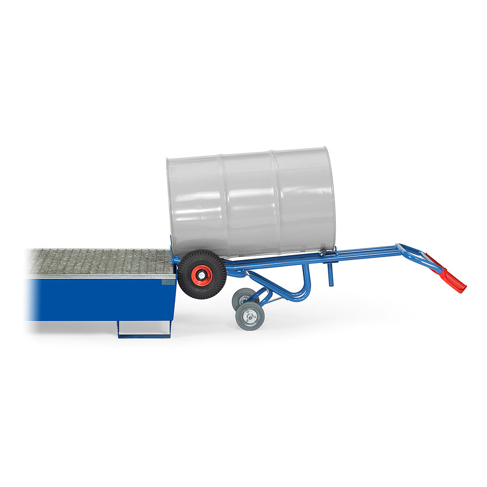 eine blaue FETRA® Karre aus Stahlrohr, mit zwei Rädern mit Luftbereifung auf roten Felgen, roten Handgriffen und geschwungener Stütze für Schräglage in Ruheposition mit zusätzlicher zweiter Achse mit zwei Stützradern, beladen mit einem grauen 200 Liter Fass aus Metall, in die Horizontale gekippt vor einer Ölwanne mit Gitterrost, freigestellt auf weißem Hintergrund